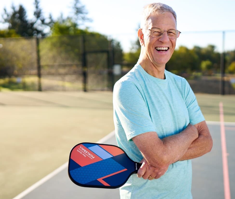 Smiling senior man on tennis court