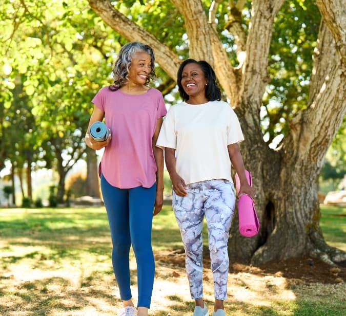 Two senior women outdoor with yoga mats