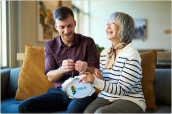 An employee helps an elderly woman with embroidery